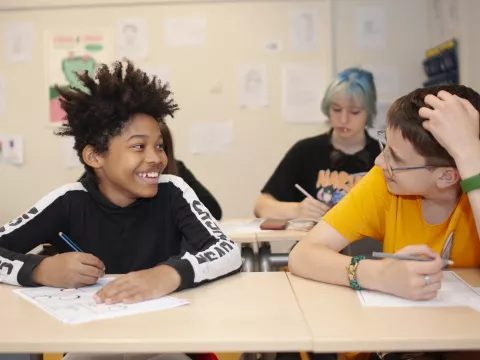 Leerlingen kijken elkaar lachend aan in het klaslokaal
