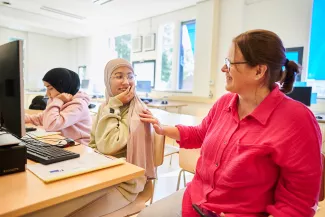 Leerlingen ISK en docent werken met de computer.